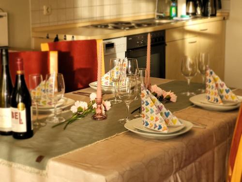 a table with plates and glasses and bottles of wine at Schaake Hooksiel - Charmante Reetdachwohnung & Kostenfreier Parkplatz in Hooksiel