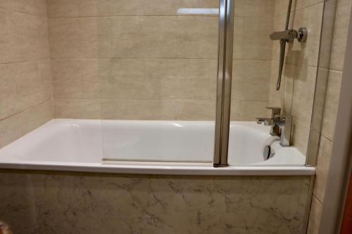 a bath tub with a glass shower door in a bathroom at The Pig Inn in Snaith