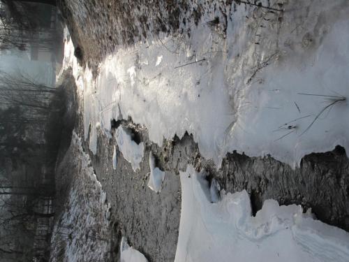 a wall covered in ice and snow next to a building at Guest House U Lakomce in Desná