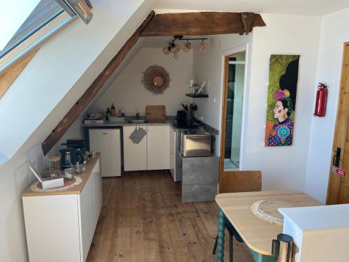 une cuisine avec des armoires blanches et un plancher en bois dans l'établissement Petit loft de charme en centre Bretagne - Brocéliande, à La Croix-Helléan