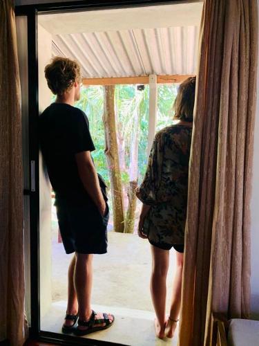 a man and a woman standing in front of a window at Solo's Shelter Hostel Udawalawa in Udawalawe