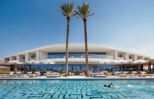 a hotel with palm trees and a swimming pool at One&Only Aesthesis, Athens in Athens
