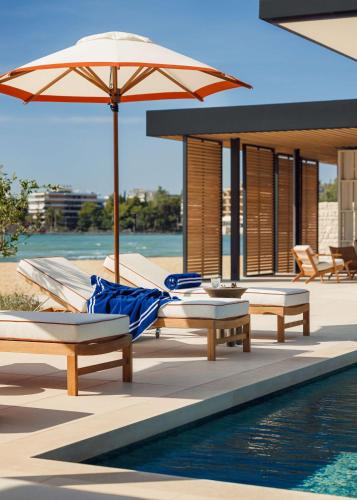a pool with benches and an umbrella next to a pool at One&Only Aesthesis, Athens in Athens