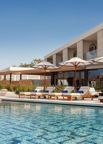 a pool with chairs and umbrellas in front of a hotel at One&Only Aesthesis, Athens in Athens