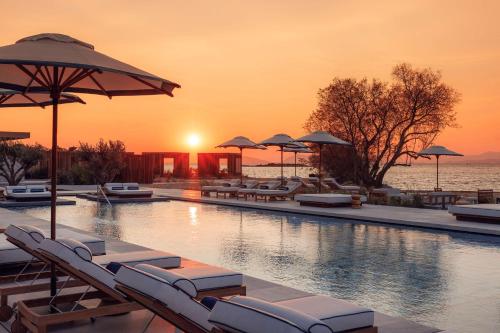 a swimming pool with lounge chairs and umbrellas at One&Only Aesthesis, Athens in Athens