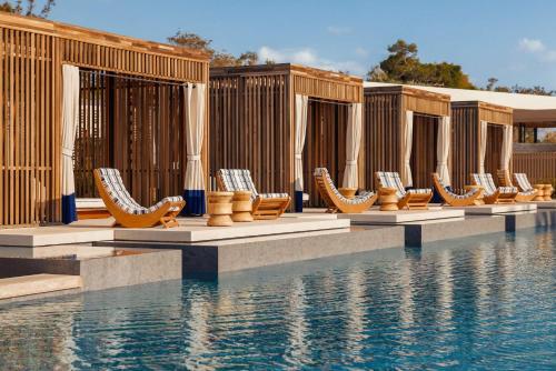 a row of lounge chairs next to a swimming pool at One&Only Aesthesis, Athens in Athens