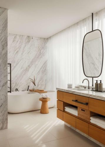 a bathroom with a tub and a sink and a mirror at One&Only Aesthesis, Athens in Athens