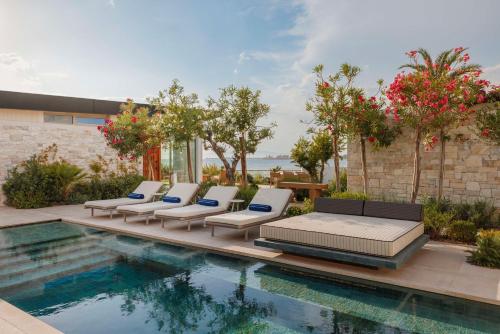 a group of lounge chairs next to a swimming pool at One&Only Aesthesis, Athens in Athens