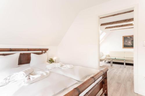 a white bedroom with a bed and a living room at Ostseebad-Zinnowitz-Kernsanierte-Maisonette-Wohnung-Himmel in Zinnowitz