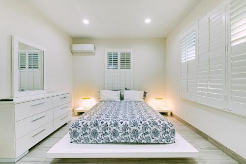 a white bedroom with a bed and two lamps at Stylish Modern Home, AC, Parking & Near FWYs in Santa Ana