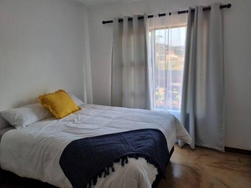 a bedroom with a bed with a window and a bedspread at Cosy Home on BedRock Base in Mbabane