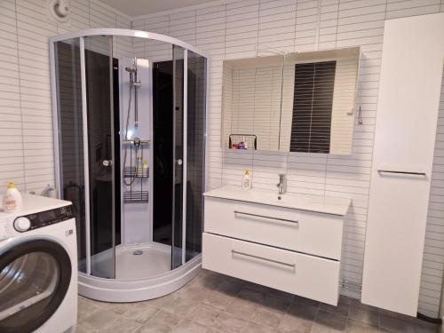 a bathroom with a shower and a sink and a washing machine at apartment With fantastic view and parking in Tromsø