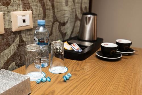 a wooden table with two glasses and a bottle of water at Sky Hotel Tirana in Tirana
