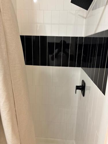 a bathroom with a shower with black and white tiles at Sweet getaway 6 min from EWR in Elizabeth