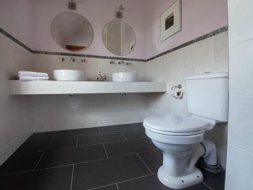 a bathroom with a white toilet and two mirrors at The Park Guest House, Stornoway in Stornoway