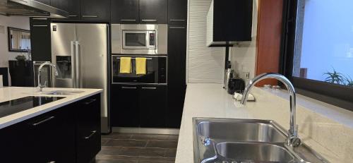 a kitchen with a sink and a stainless steel refrigerator at Petit Maison in Além da Ribeira