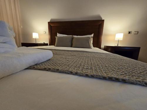 a bedroom with a large bed with two lamps at Petit Maison in Além da Ribeira