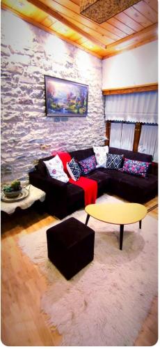 a living room with a couch and a stone wall at Ela's Chalet in Old Bazaar Gjirokaster in Gjirokastër