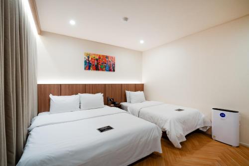 two beds in a room with white sheets at Hotel Laglas Asan in Asan