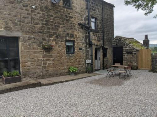 a stone building with a table in front of it at 1 Hillside Cottages in Leeds