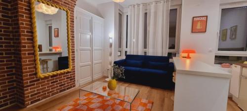 ein Wohnzimmer mit einem blauen Sofa und einem Spiegel in der Unterkunft PALM SPRINGS - Art Deco au cœur de Malo-les-Bains in Dunkerque
