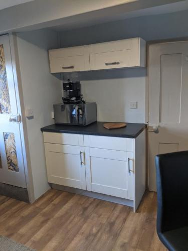 a kitchen with white cabinets and a black counter top at 1 Hillside Cottages in Leeds