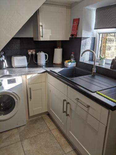 a kitchen with a sink and a washing machine at 1 Hillside Cottages in Leeds