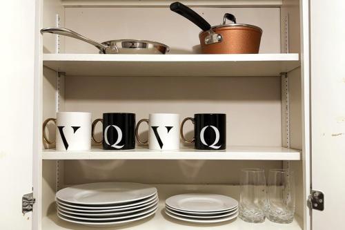 a cupboard with plates and utensils in it at Cozy Comfort Stay Moncton - 2 Bedrooms with Kitchen and Parking in Moncton