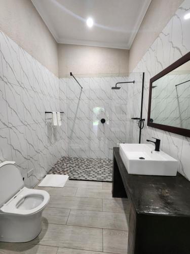 a bathroom with a toilet and a sink at Jacaranda Lodge in Victoria Falls