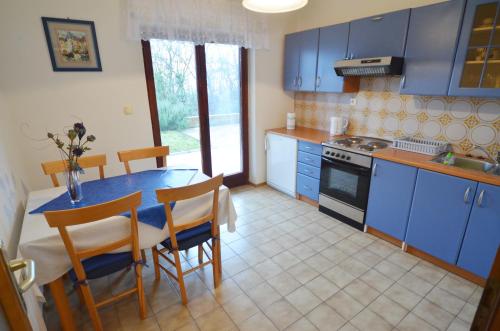 a kitchen with blue cabinets and a table and chairs at Green Apartments in Matulji