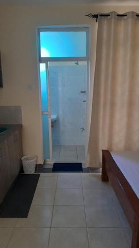 a bathroom with a shower with a window and a door at MJ homes in Mtwapa