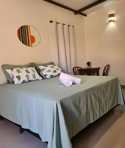 a bedroom with a large bed with pillows and a table at Chalé À800Mts do Parq Chapada dos Veadeiros, Wi-fi in Alto Paraíso de Goiás