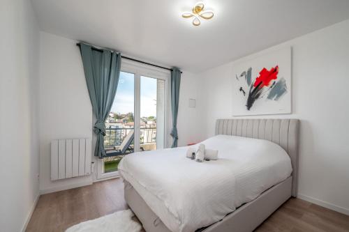 une chambre avec un lit blanc et une fenêtre dans l'établissement 3 pièces cocon dans les hauteurs de Cannes vue mer, au Cannet