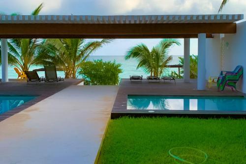 a house with a pool and a patio with chairs at Kasos ground level apartment in Chicxulub