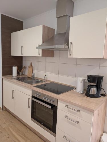 a kitchen with white cabinets and a stove top oven at Pension zum Reiterhof, Fewo 2 in Schmogrow