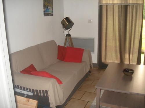- un salon avec un canapé et 2 oreillers rouges dans l'établissement Maison à la campagne, à Paslières