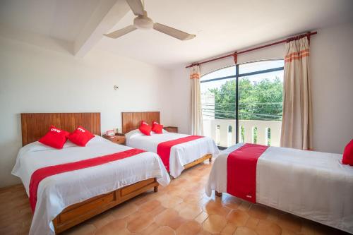 a bedroom with two beds with red pillows at Arena Surf Hotel, Puerto Escondido in Puerto Escondido