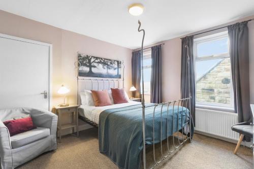 a bedroom with a bed and a chair and a window at Wyndgrove House - North East Escapes in Seahouses