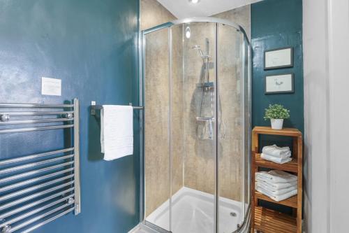 a shower in a bathroom with blue walls at Wyndgrove House - North East Escapes in Seahouses