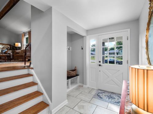 a hallway with a white door and a staircase at Two Entire Homes with Hot Tubs and Games Sleeps 20 in Akron