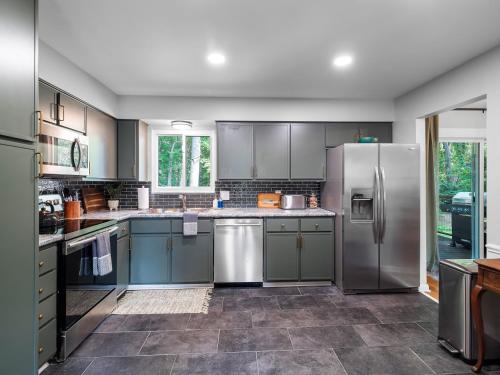 a kitchen with gray cabinets and stainless steel appliances at Two Entire Homes with Hot Tubs and Games Sleeps 20 in Akron