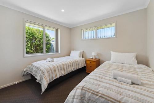 two beds in a room with two windows at Delight in the Dell - 2 mins to lake in Taupo