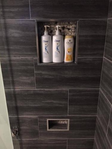 three shampoo bottles sitting on a shelf in a bathroom at Upscale 2-Bedroom Basement Apartment in London