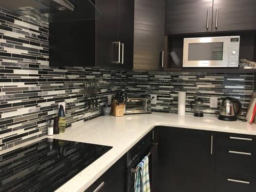 a kitchen with black cabinets and a microwave at Comfy 3-Bedroom Home with Modern Upgrades in London