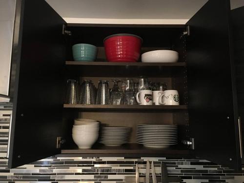 a black cabinet with plates and cups and bowls at Comfy 3-Bedroom Home with Modern Upgrades in London