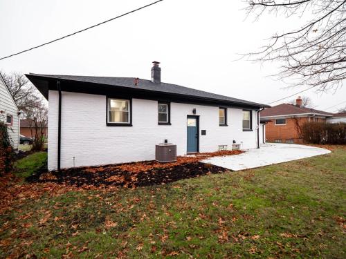a white house with a blue door in a yard at Luxurious Retreat with Sauna and Modern Design in Warrensville Heights