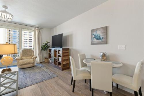 a living room with a dining area with a table and chairs at Shores of Panama 727 - Same level parking space! in Panama City Beach