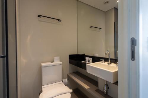 a bathroom with a white toilet and a sink at 360 VN Turiassú by Housi in Sao Paulo