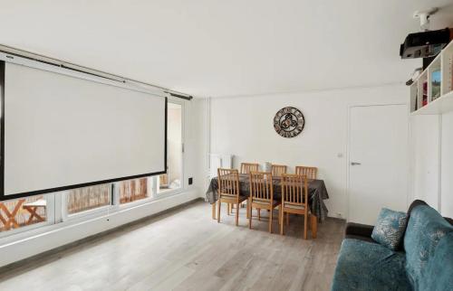 un salon avec une table et un grand écran dans l'établissement Le cocon, à Nanterre