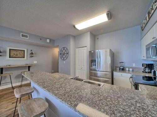 a kitchen with a counter top and a refrigerator at Shores of Panama 1307, Two Masters! Under 25 ok! in Panama City Beach